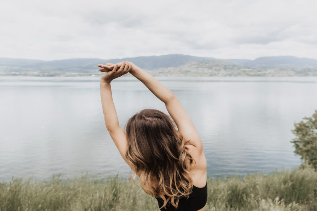 Woman stretching outside with view of lake